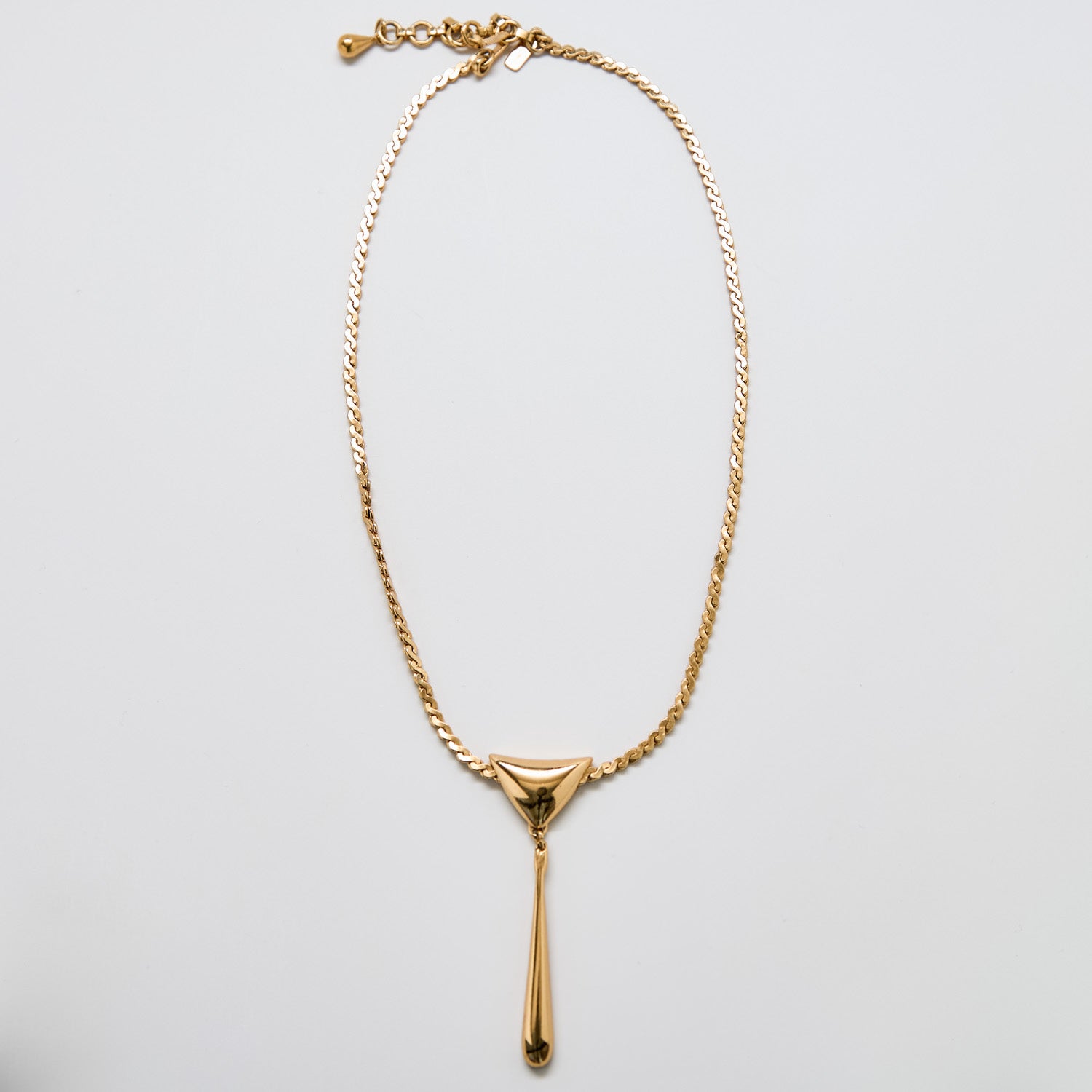 Full view of vintage Monet gold-tone pendant necklace with triangular and teardrop drop design, adjustable chain, and signed clasp.