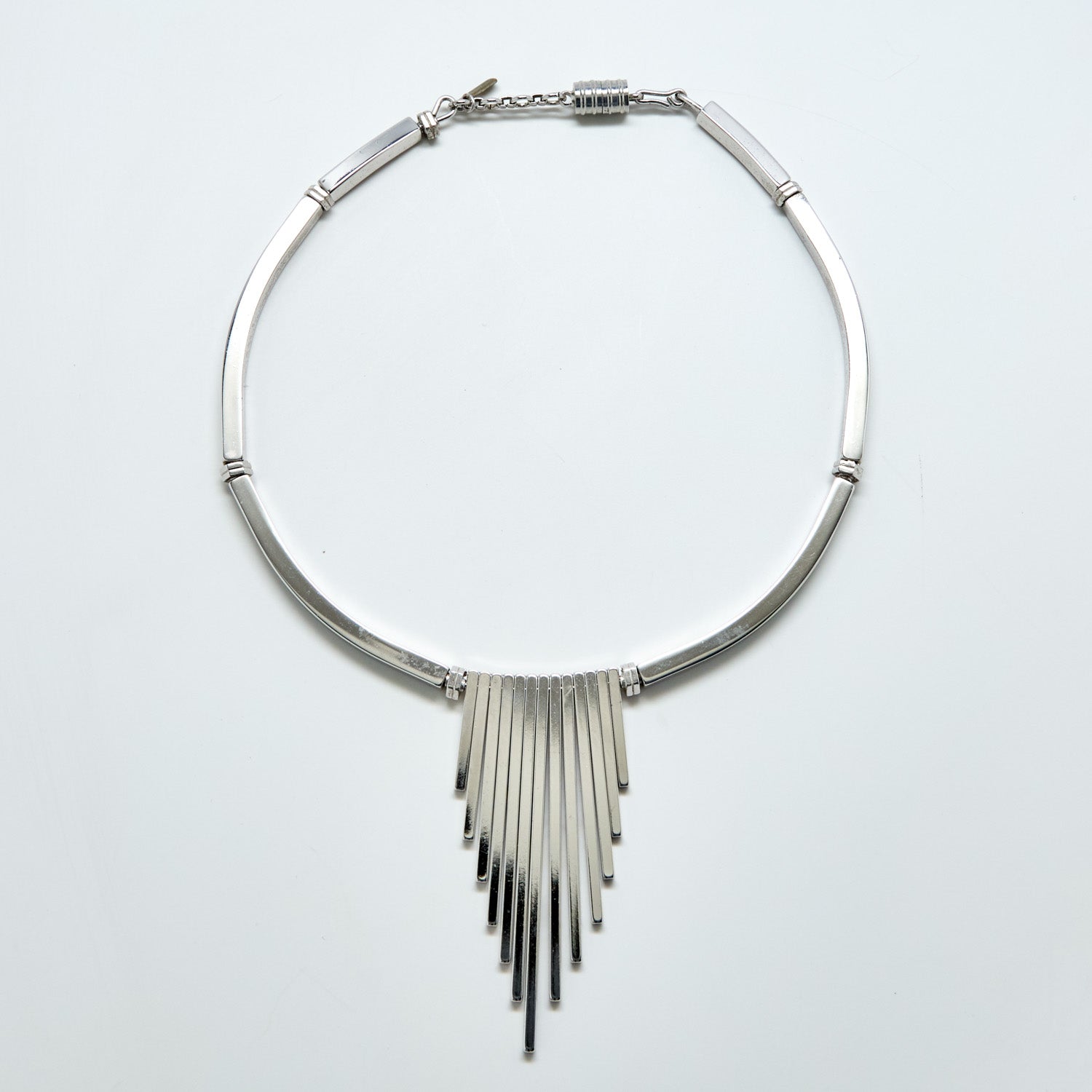 Silver fringe necklace on a light gray background