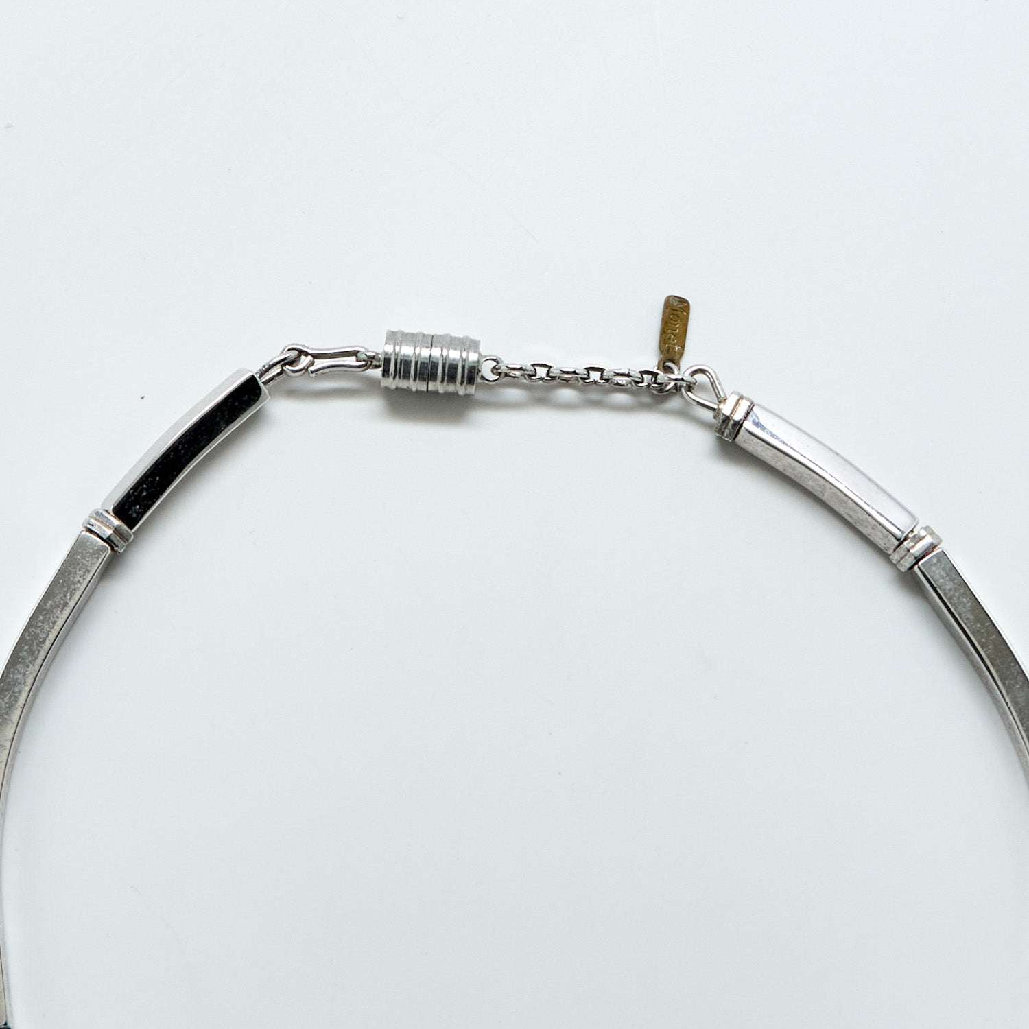 Silver necklace clasp and Monet tag on a white background