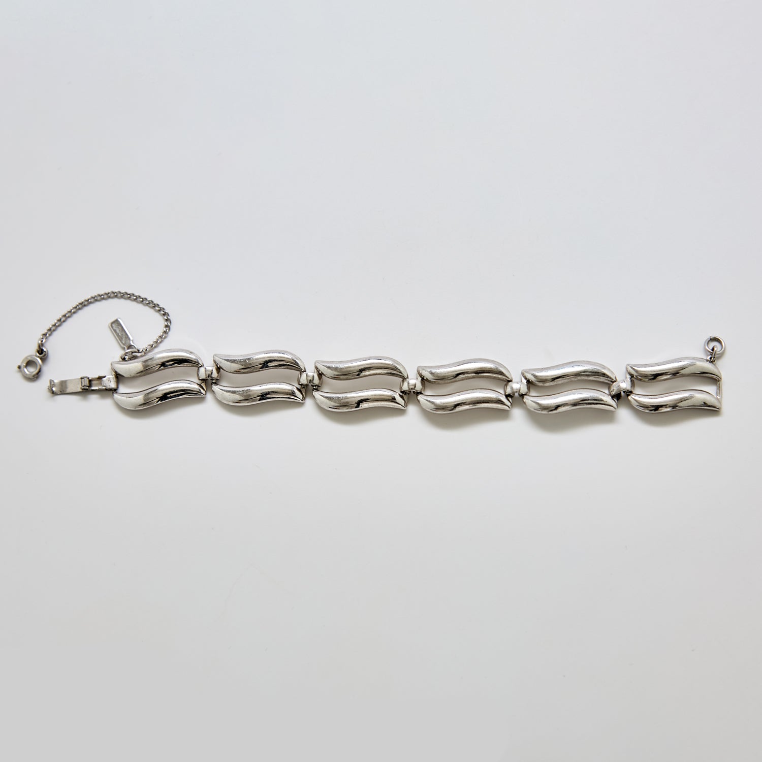 Front view of vintage Monet silver-tone bracelet featuring sculptural wave-style links and safety chain clasp.