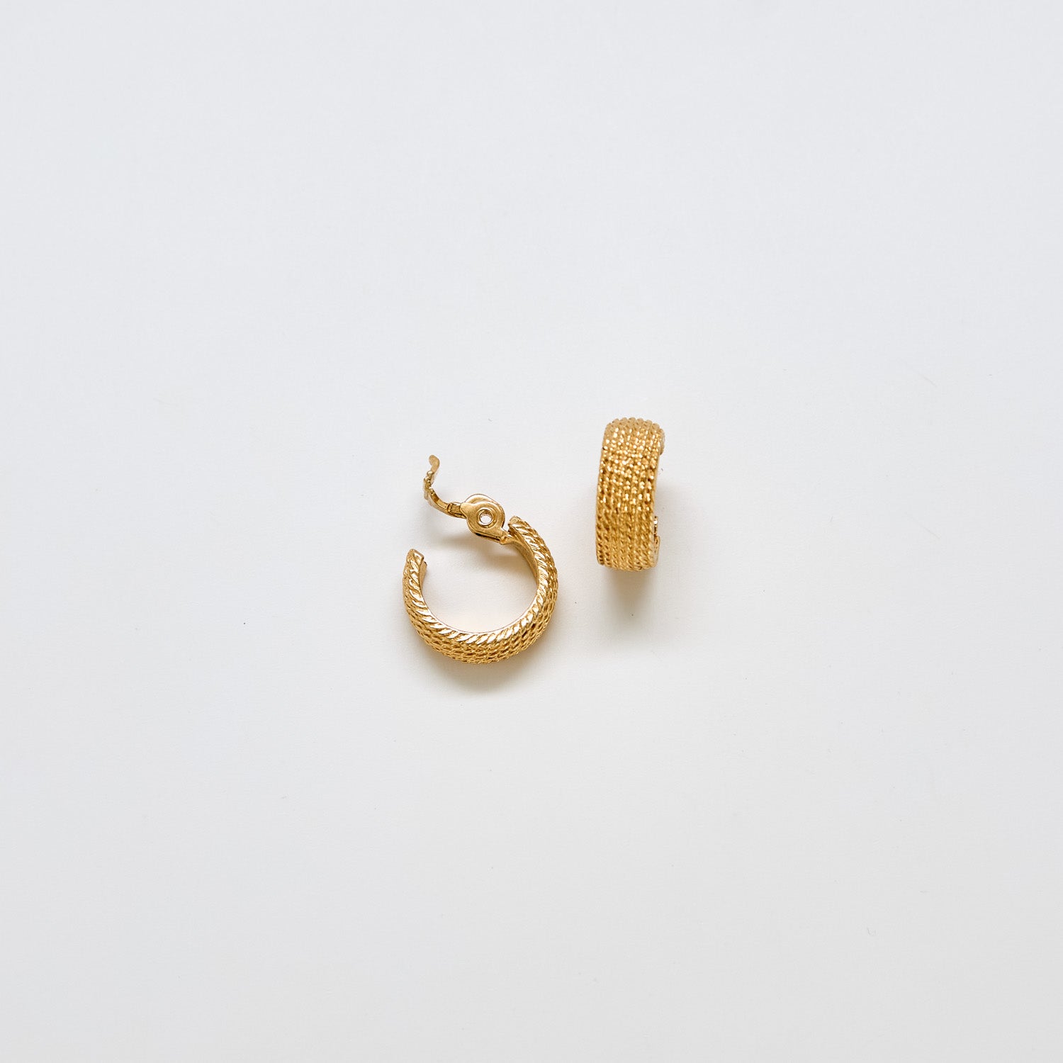 Close-up of vintage Monet textured gold hoop earrings showing fine woven detail and open clip design