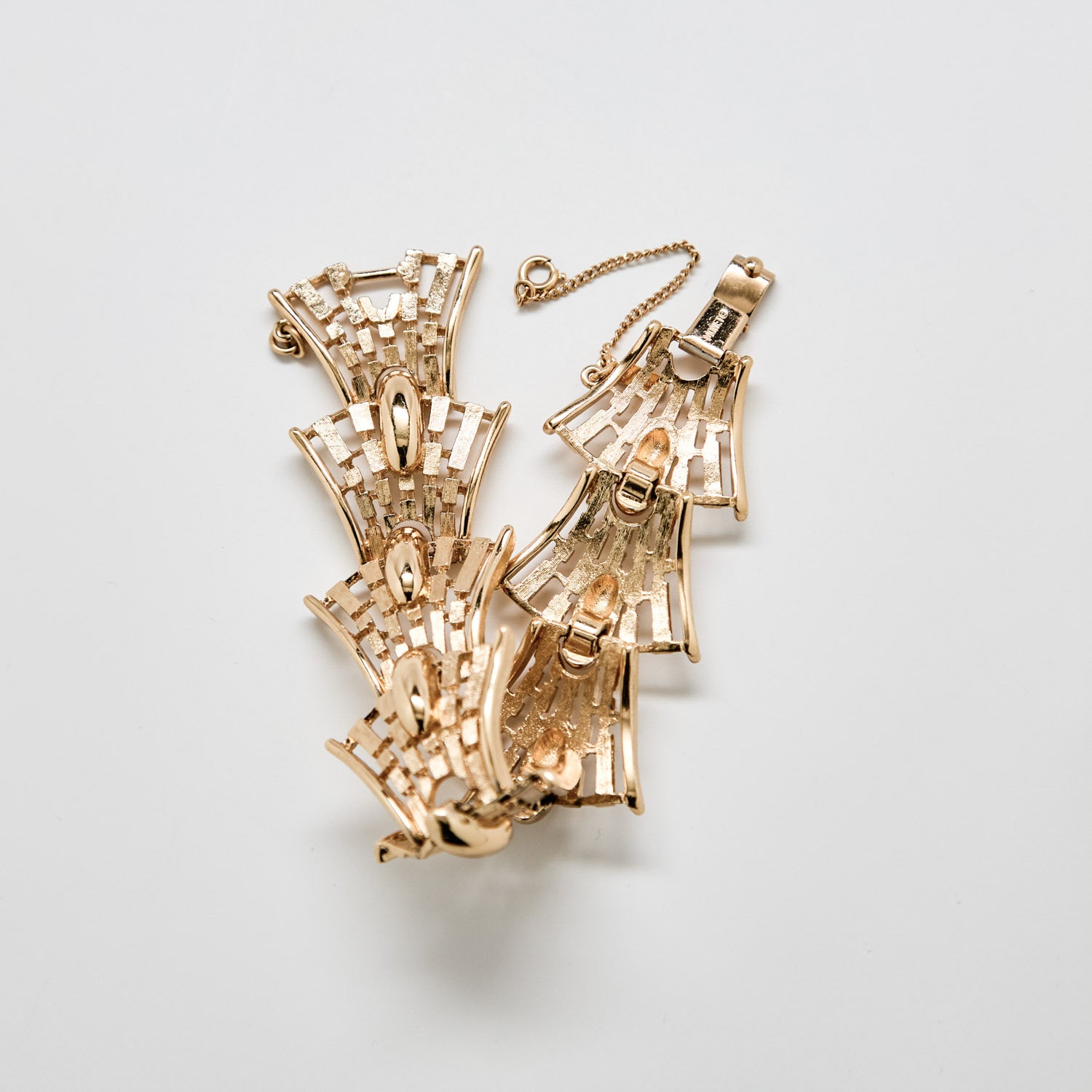 Gold necklace with intricate design on a light gray background