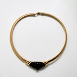 Gold necklace with a black pendant on a white background