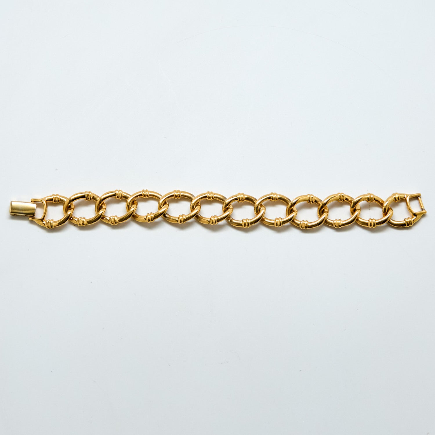Gold chain bracelet on a light gray background