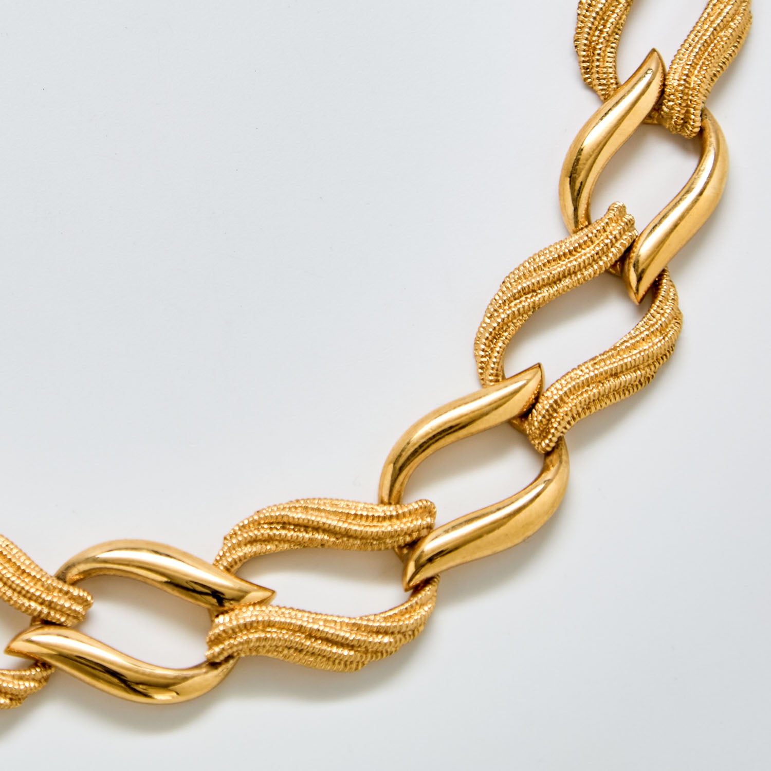 Close-up of vintage Napier necklace showing interwoven gold mesh texture and polished curved links.