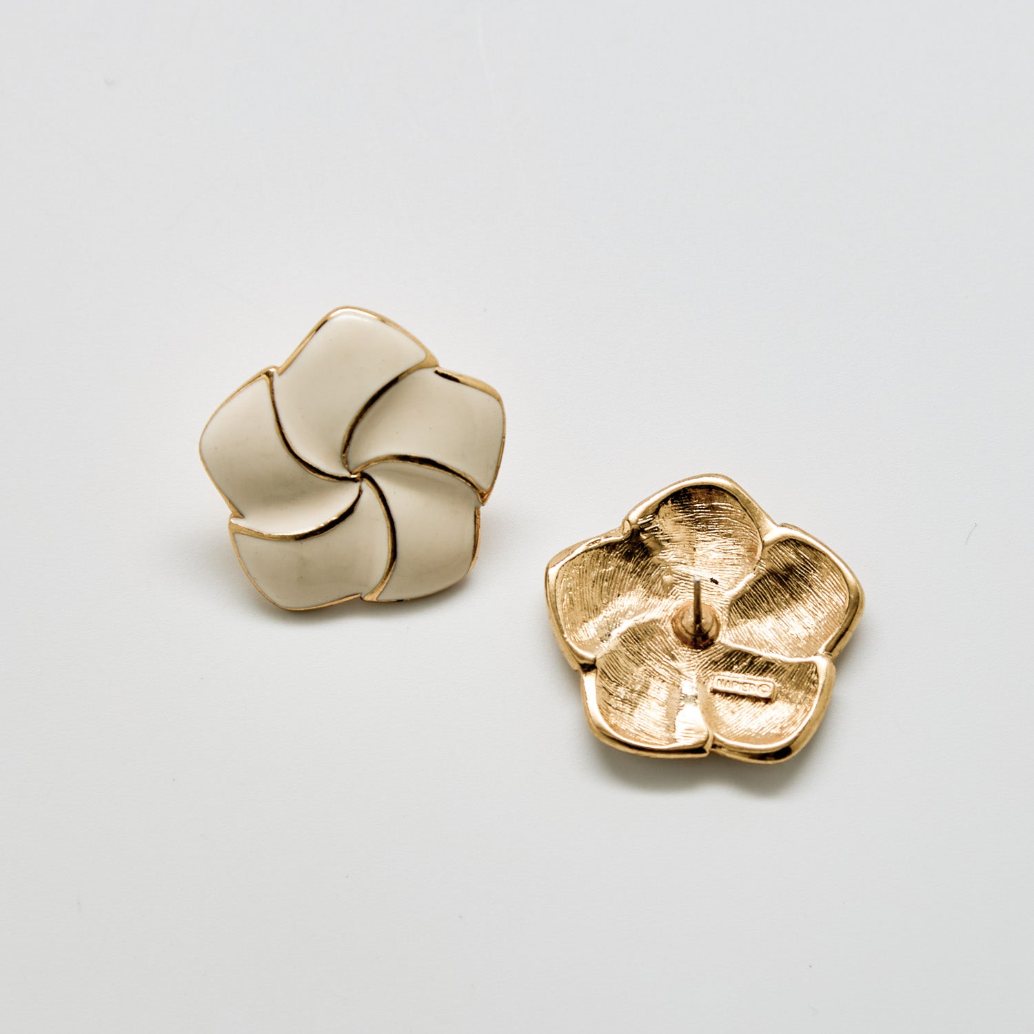 Pair of gold floral earrings on a light gray background