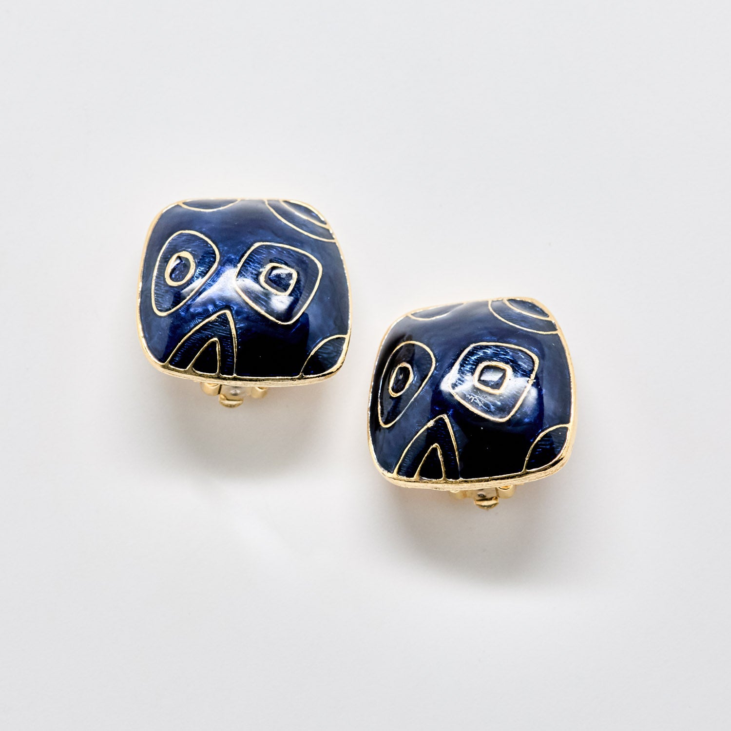 Pair of blue and gold earrings on a light gray background