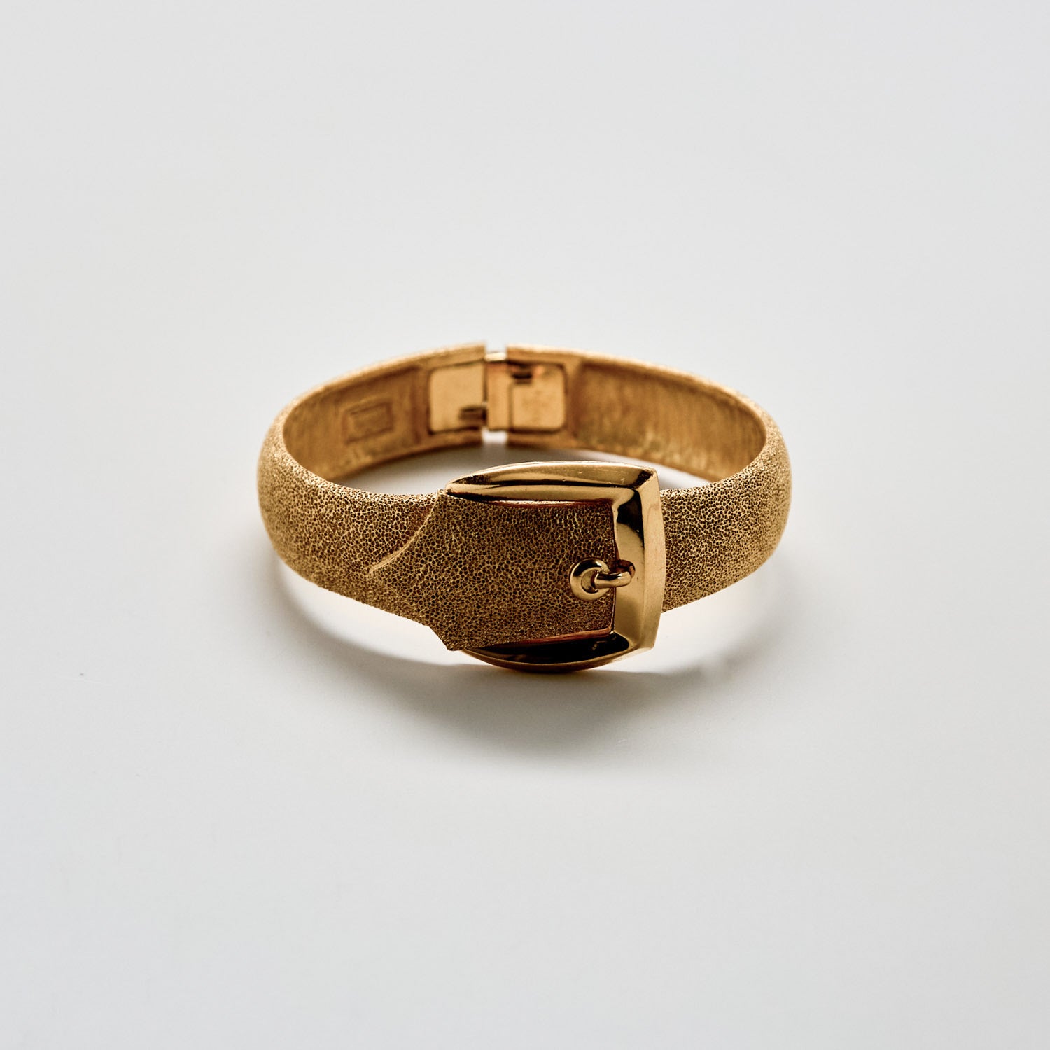 Gold bracelet on a light gray background