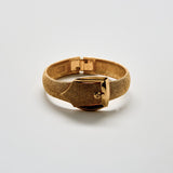 Gold bracelet on a light gray background