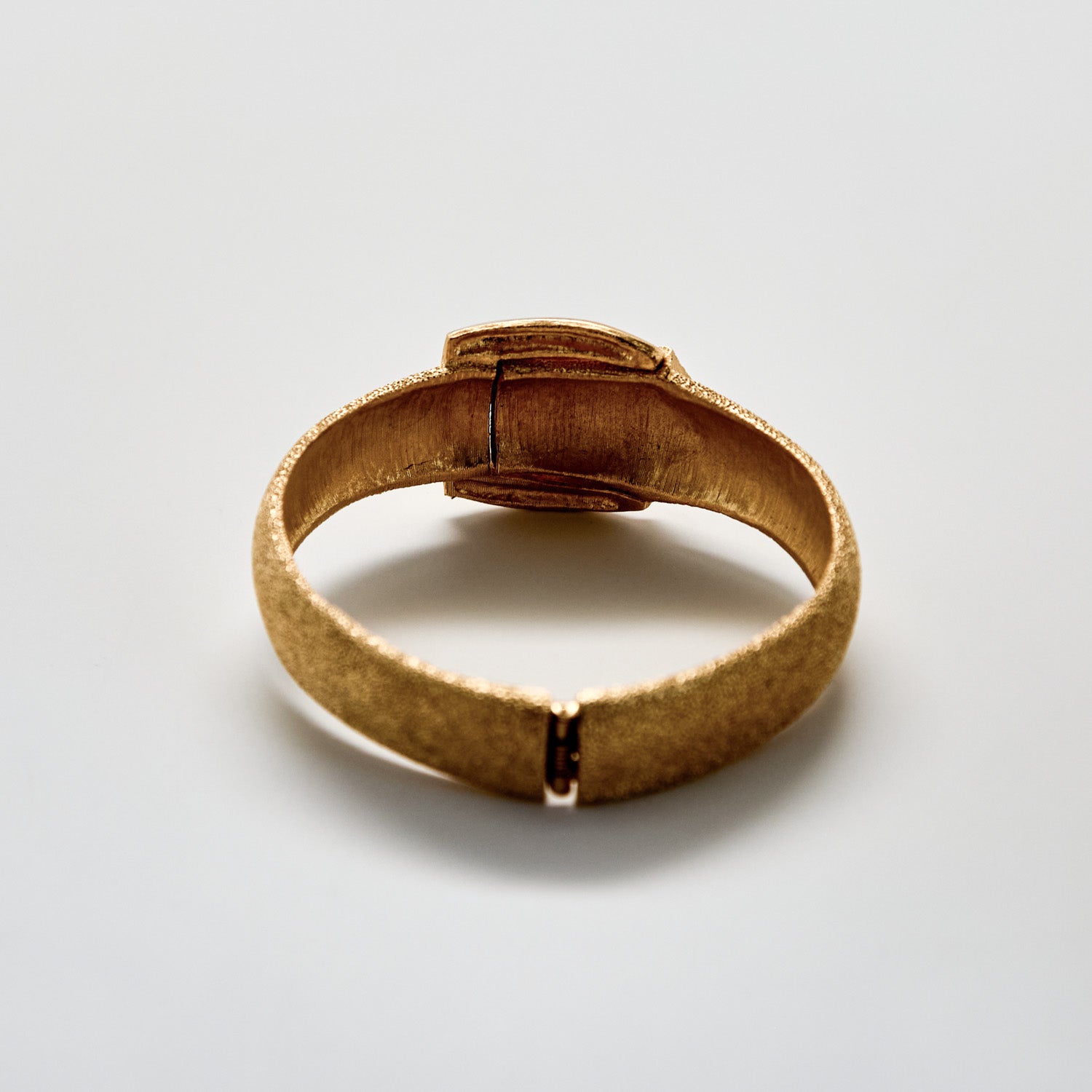 Gold ring with a textured band on a light gray background