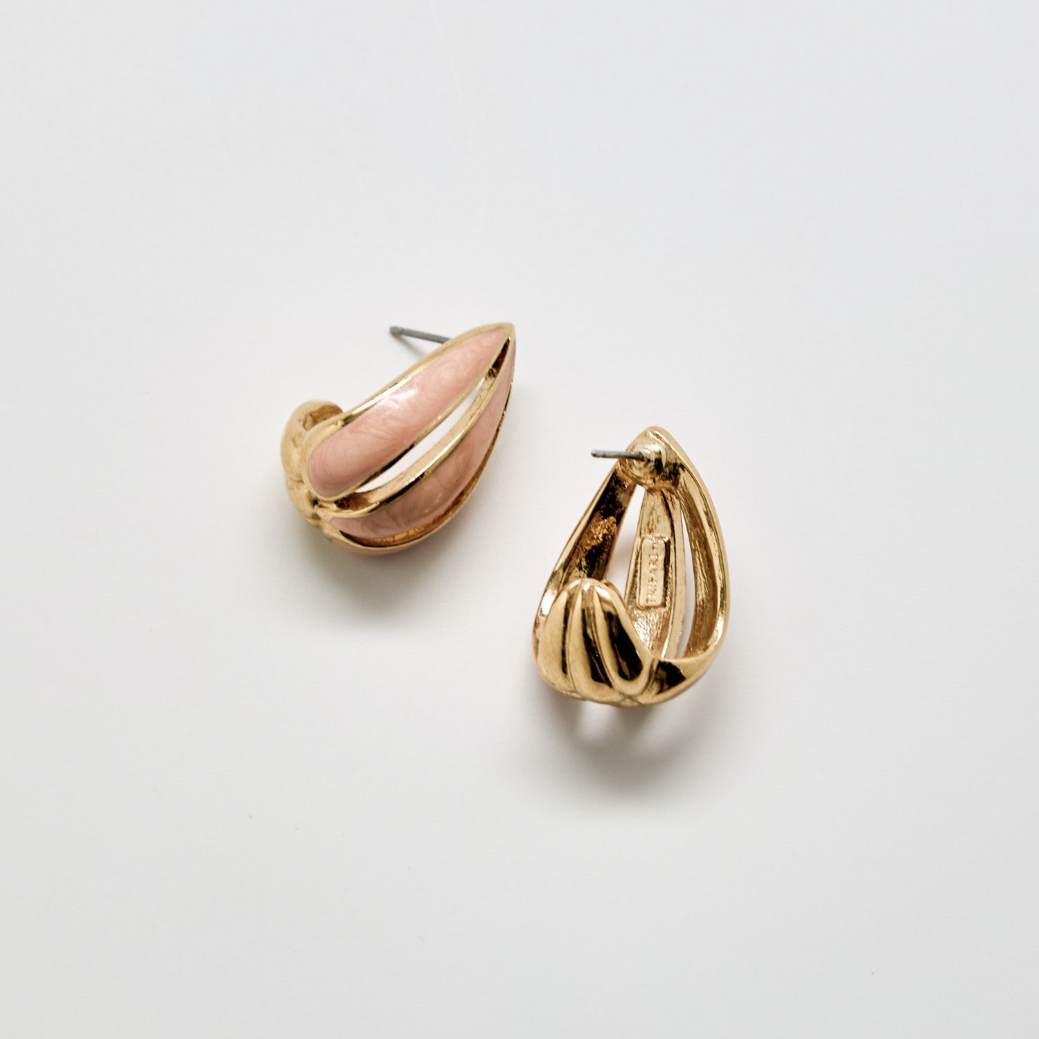 Gold and pink earrings on a light gray background