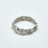 Silver ring with textured design on a light gray background