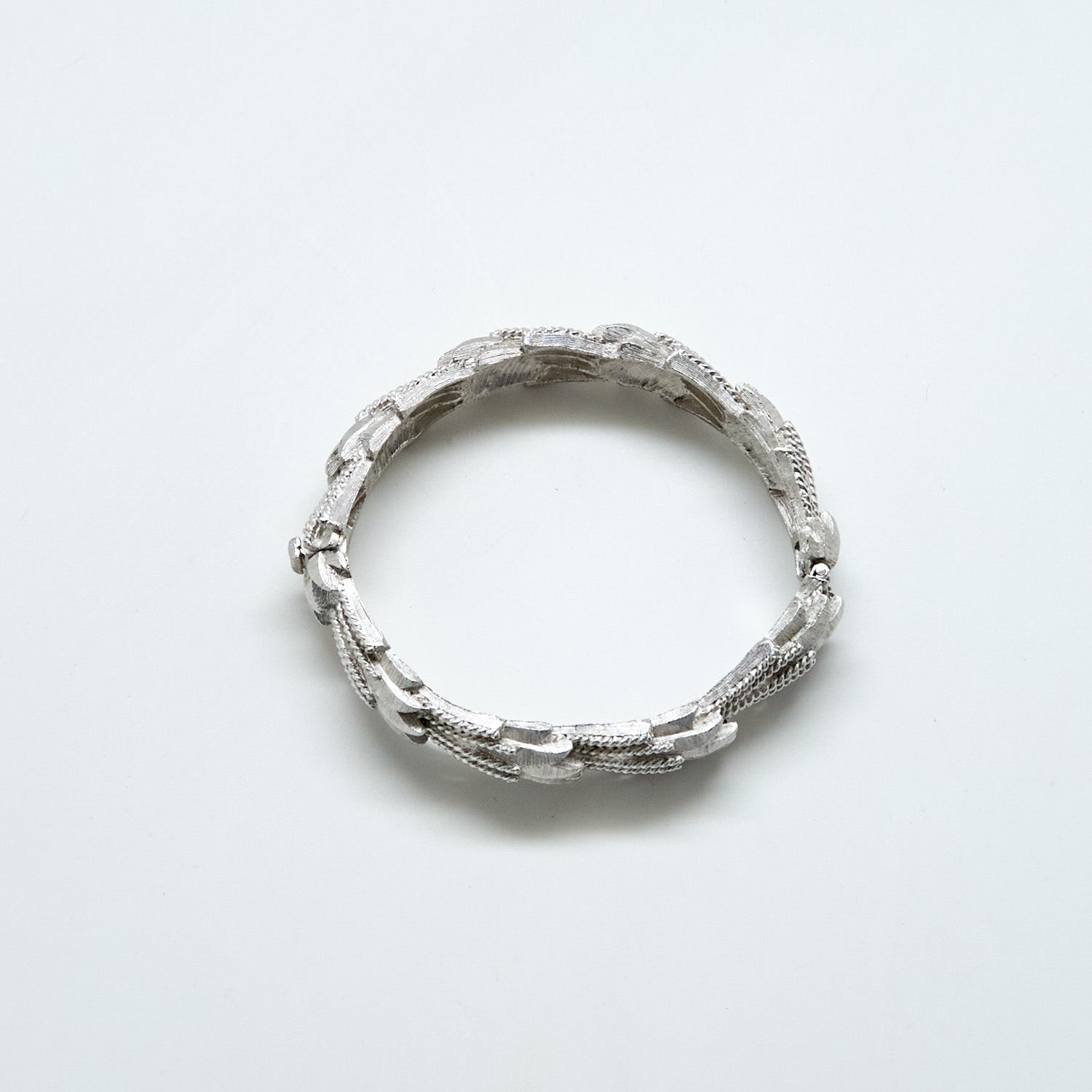 Silver ring with textured design on a light gray background