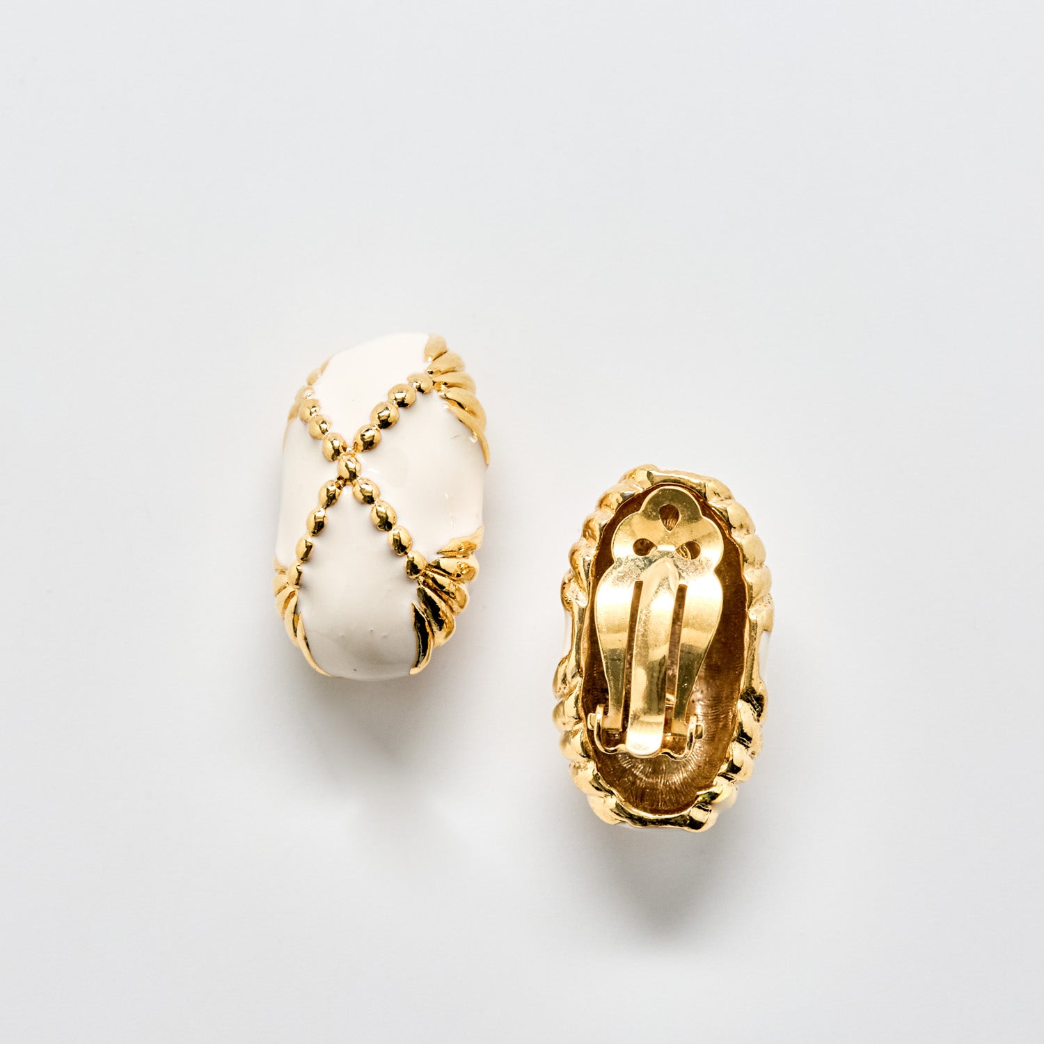 Pair of gold and white earrings on a light gray background