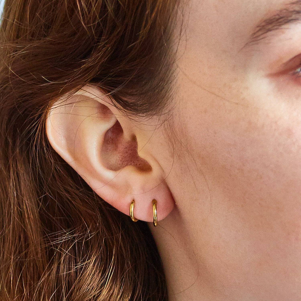 Two small gold hoops worn together in adjacent lobe piercings
