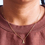 Gold letter A initial necklace worn on a model