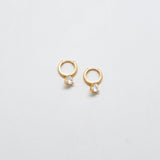 Gold CZ heart huggie earrings on white background.