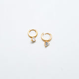 Gold huggie earrings with heart-shaped cubic zirconia accent and hinged hoop closure.