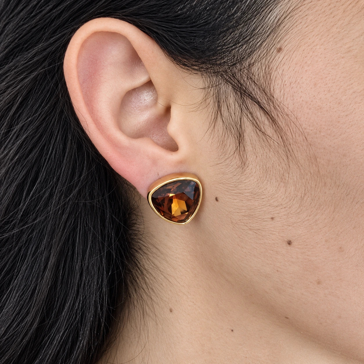 Vintage Swarovski amber-tone triangle stud earring — on-ear view
