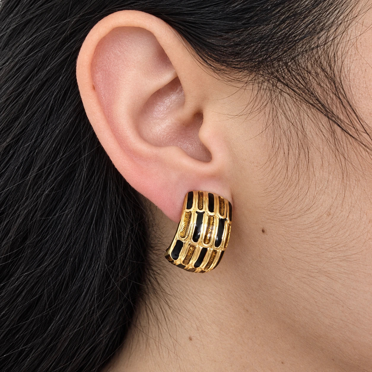 Vintage Erwin Pearl black-and-gold grid clip-on earring — on-ear view
