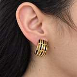 Vintage Erwin Pearl black-and-gold grid clip-on earring — on-ear view