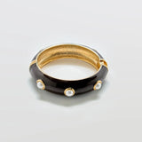 Vintage Cookie Lee brown enamel and faux pearl hinged bangle bracelet on a light gray background