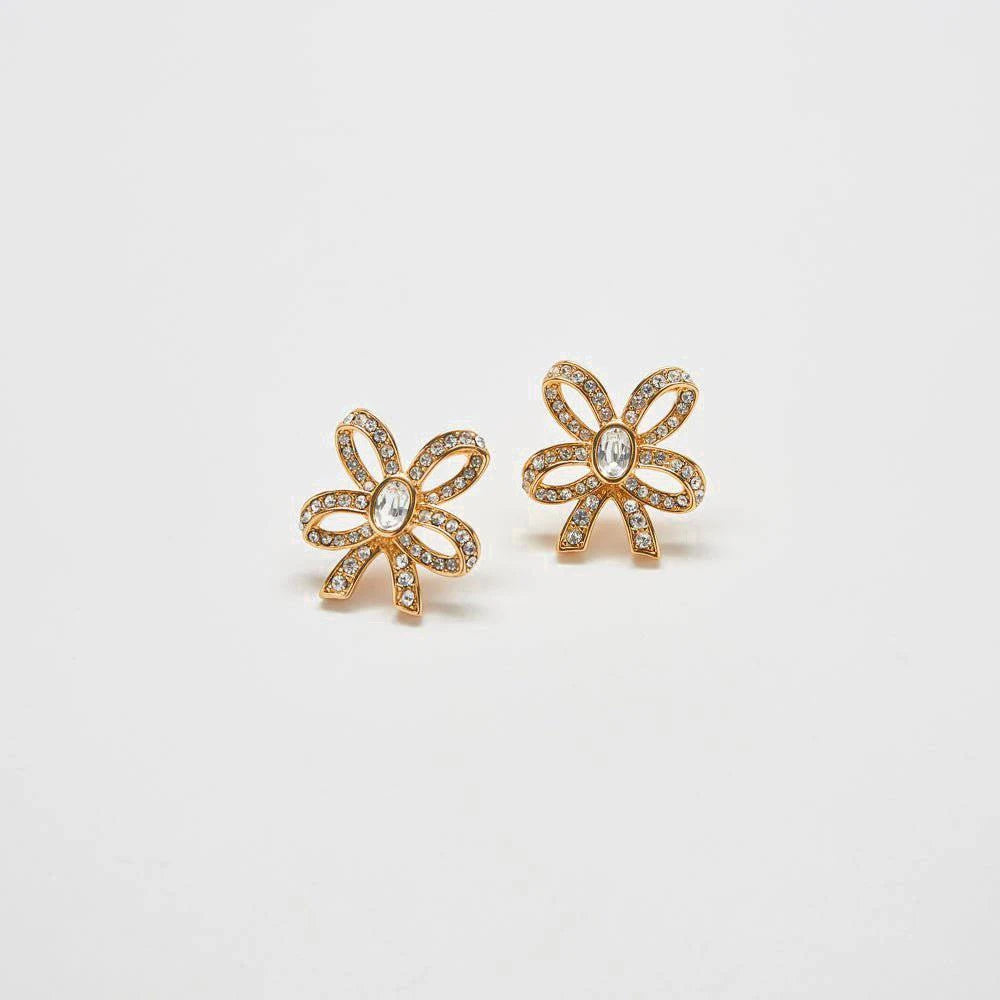 Pair of vintage pavé gold bow earrings on a light gray background