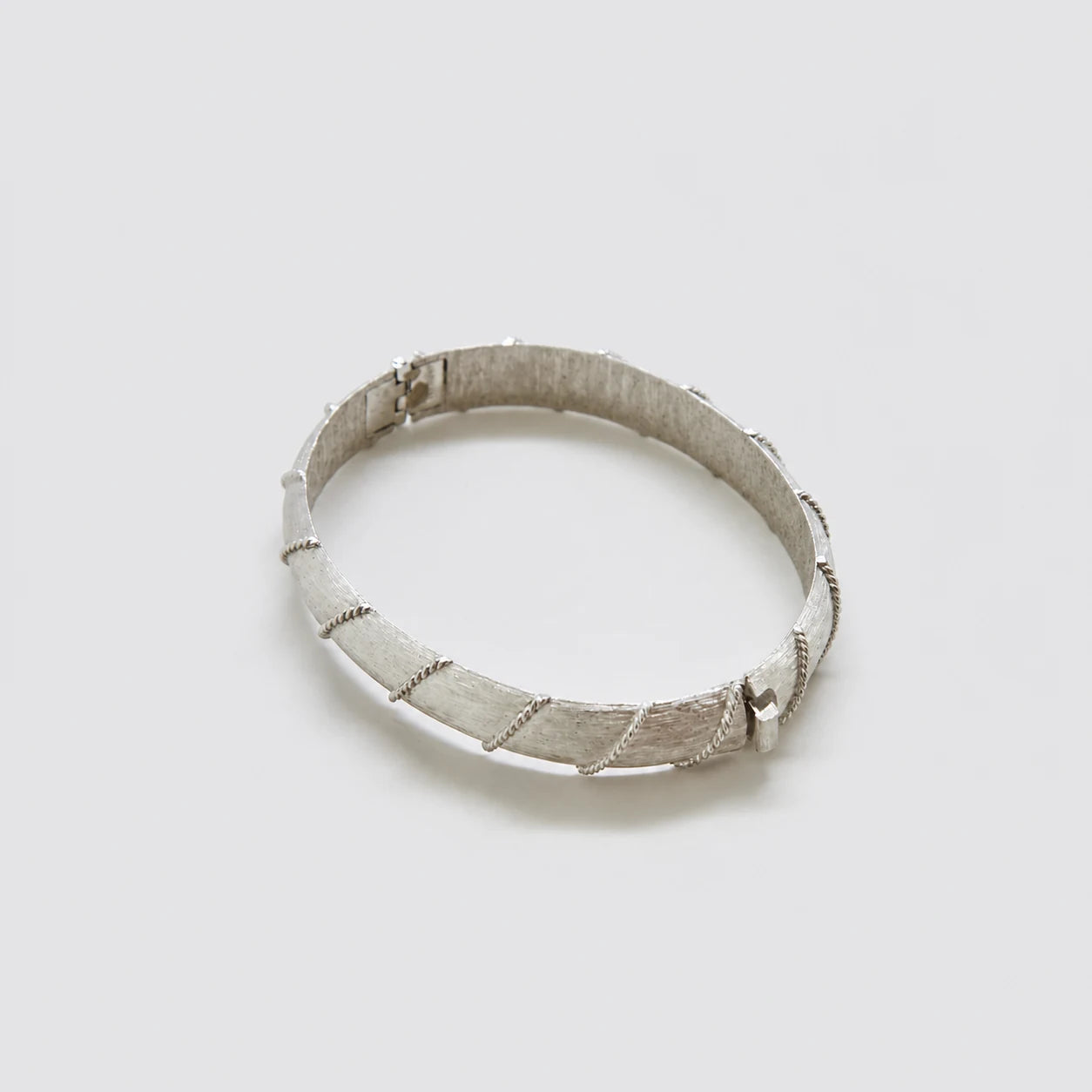 Vintage silver-tone textured hinged bangle — angled clasp view