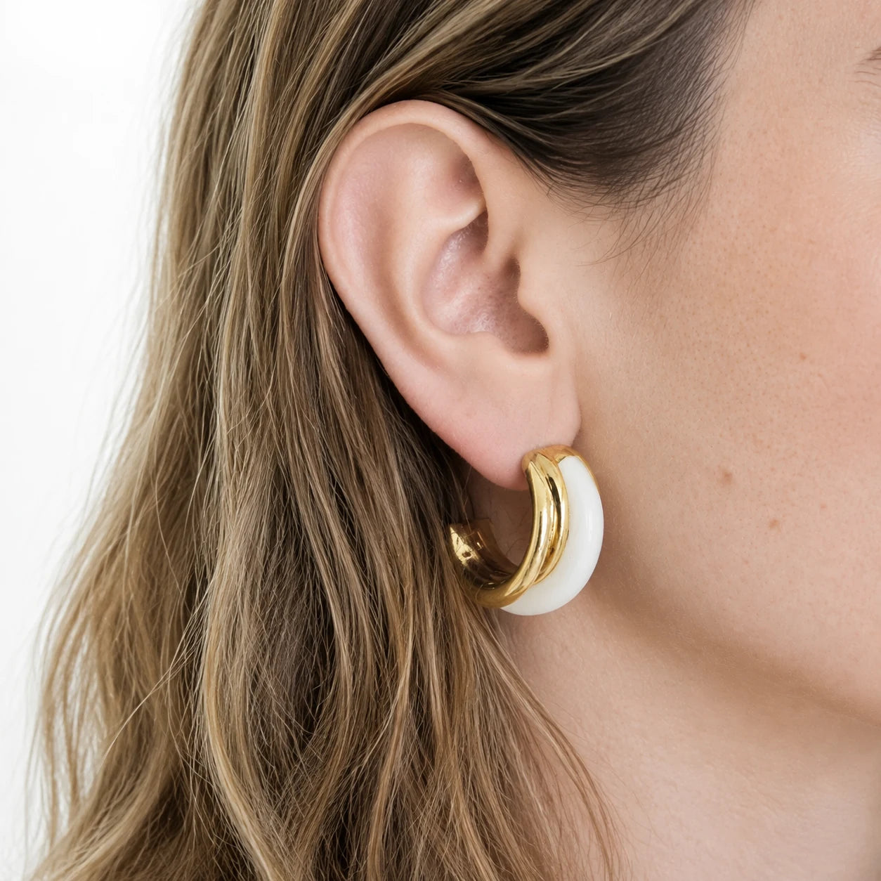 Vintage white enamel hoop earrings worn on model — side view