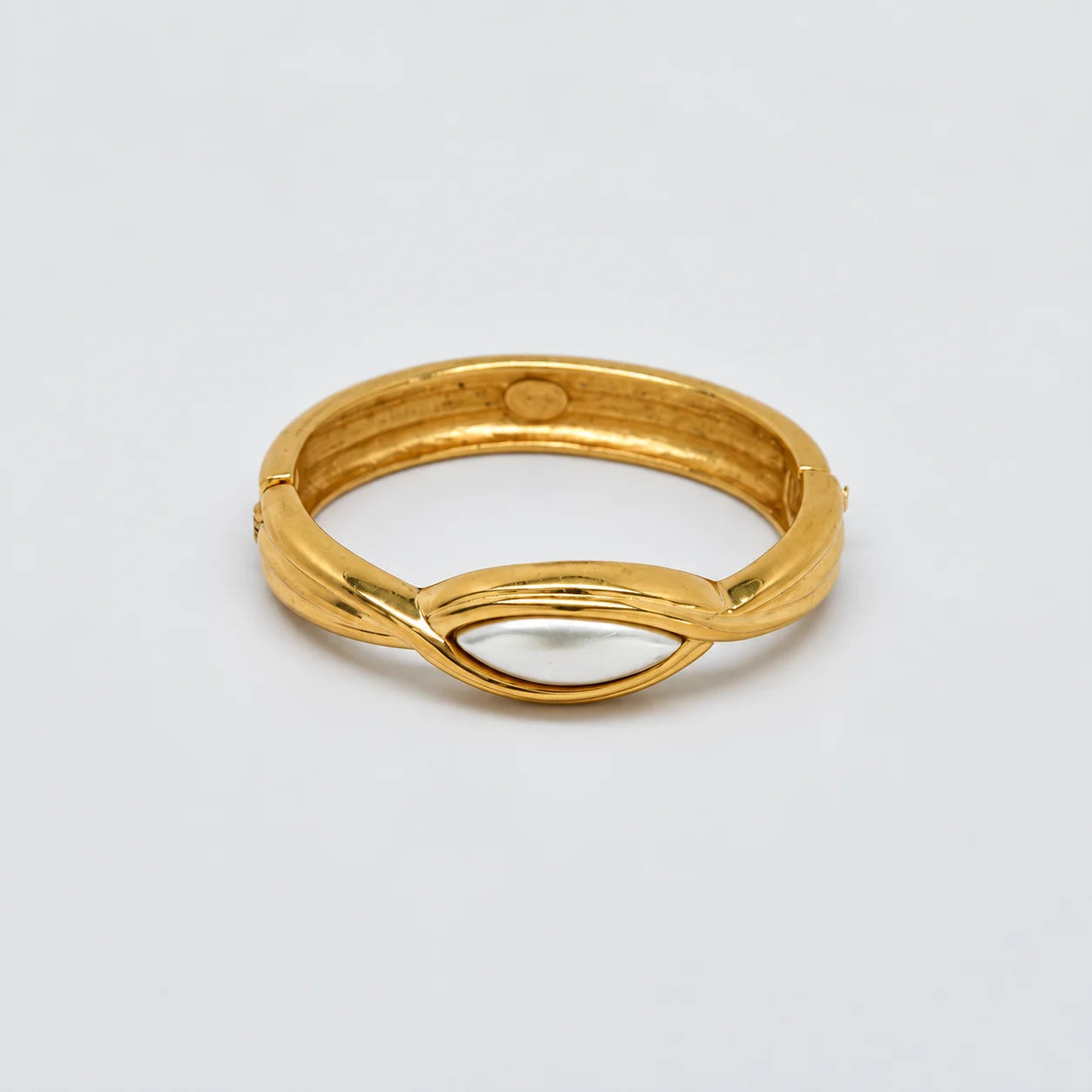 Vintage gold-tone hinged bangle with white oval centerpiece — closed