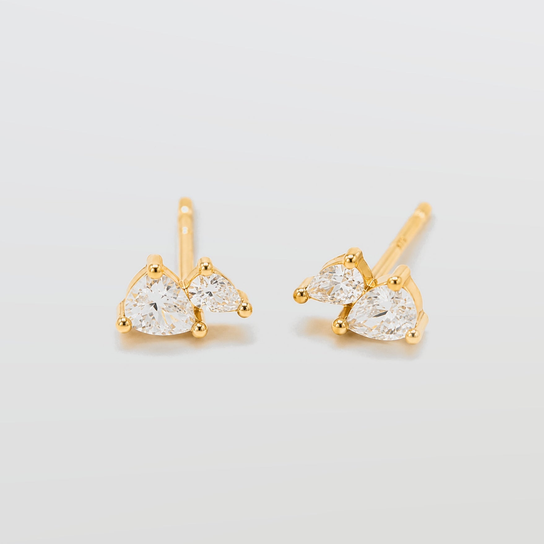Gold earrings with clear gemstones on a light gray background