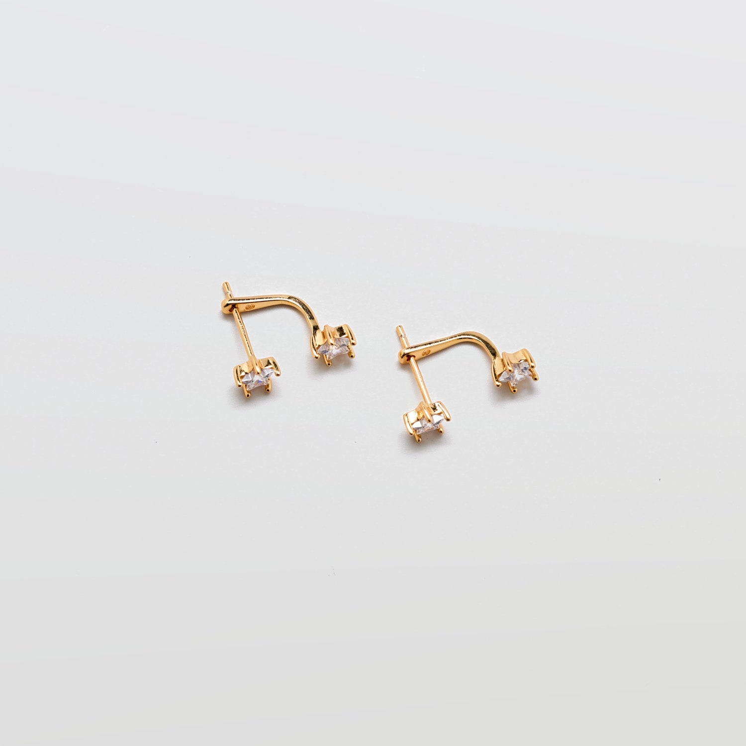 Gold cubic zirconia double stud ear jacket earrings with curved crystal accent on white background.