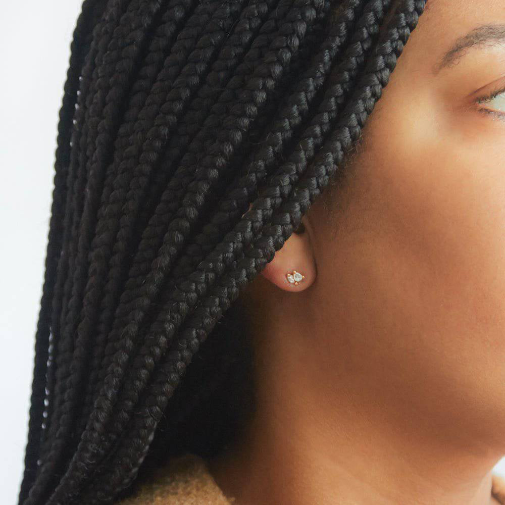 Close-up of a person wearing a double teardrop stud earring with braided hair.