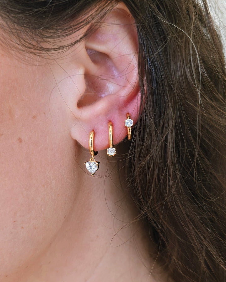 A curated ear wearing modern gold huggie hoops