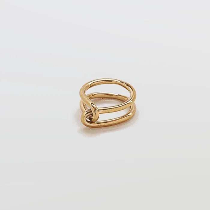 Gold double knot ring on a light gray background