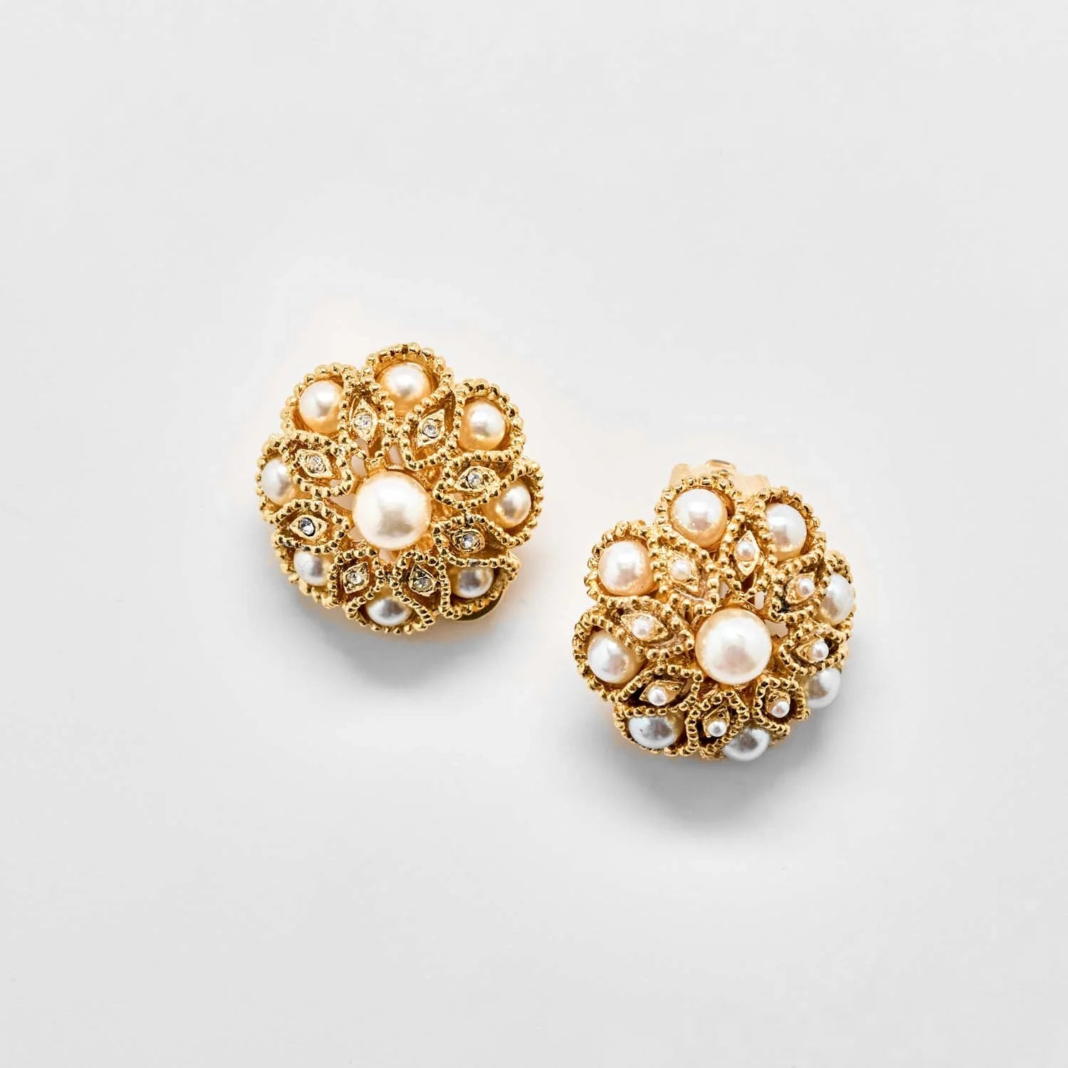 Vintage gold pearl and crystal floral clip-on earrings on a light gray background