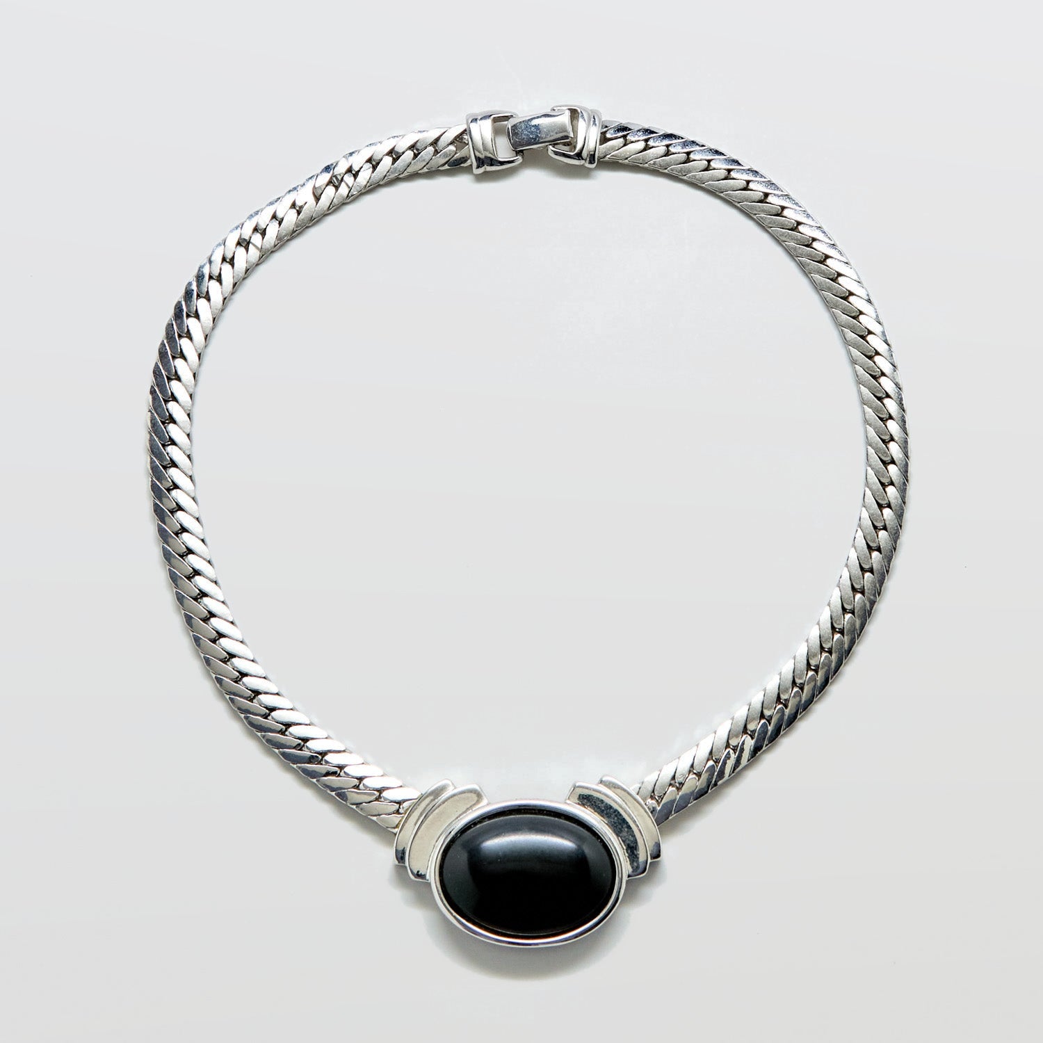 Silver bracelet with a black stone on a light gray background