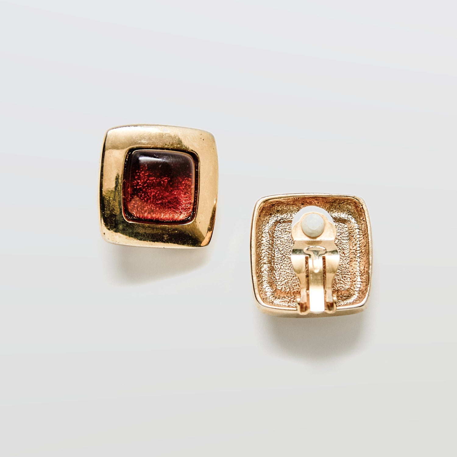 Gold earrings with a brown gemstone on a white background
