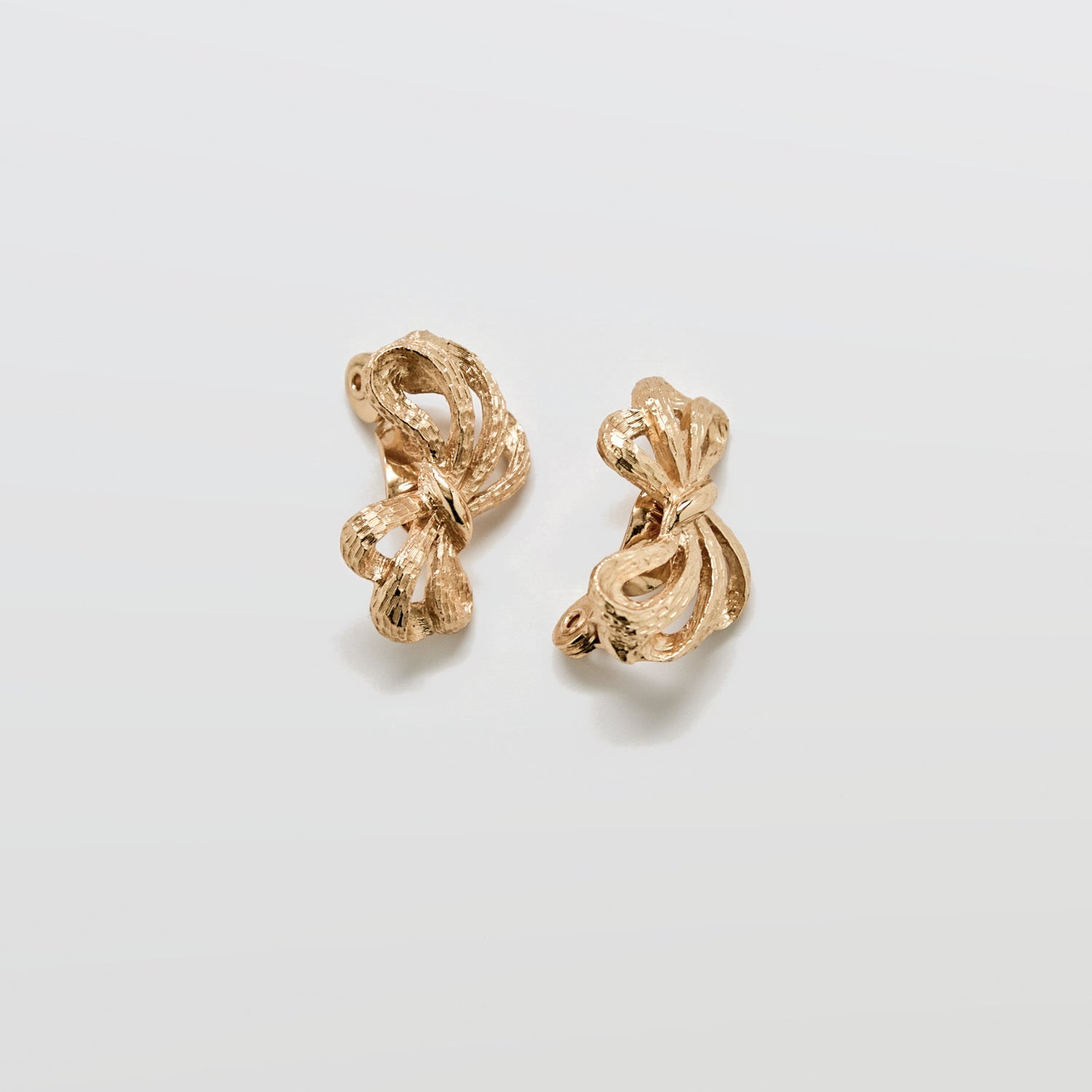 Pair of gold earrings on a light gray background