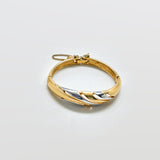 Gold bracelet with a two-tone design on a light gray background