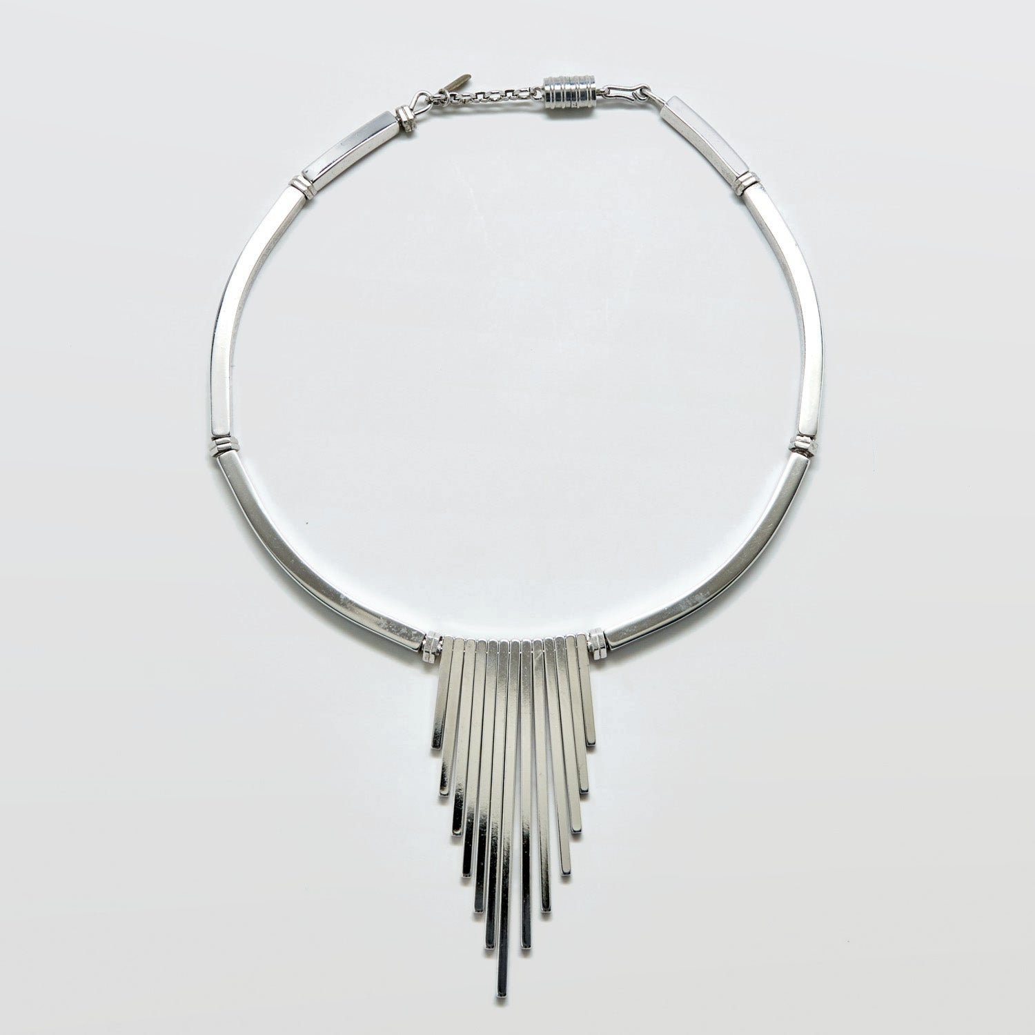 Silver fringe necklace on a light gray background