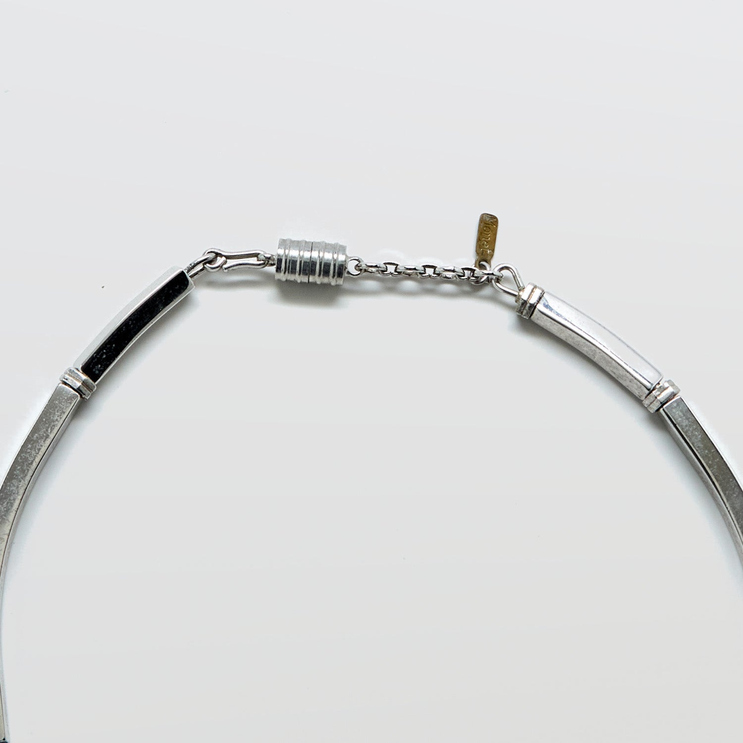 Silver necklace clasp and Monet tag on a white background