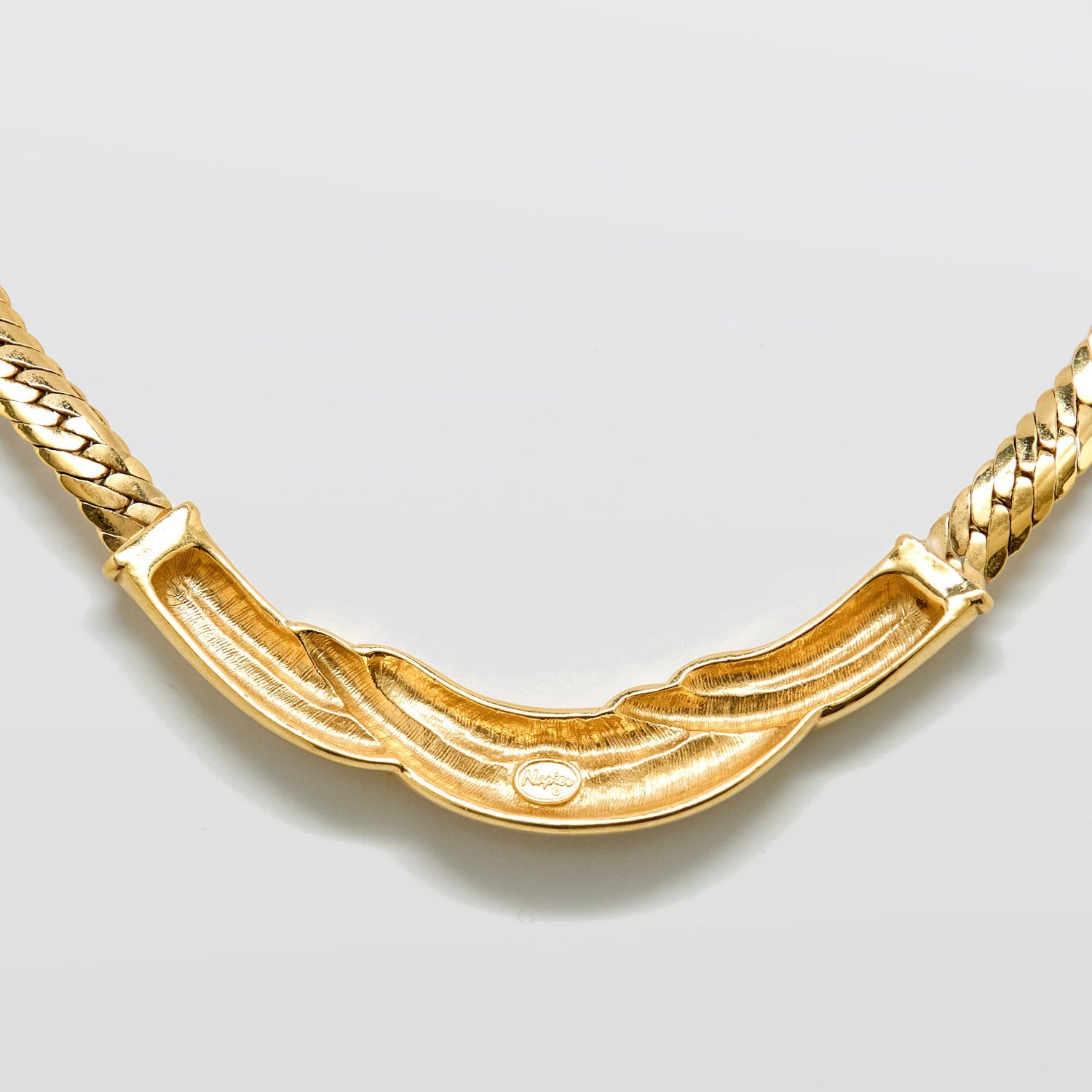 Gold necklace on a light gray background