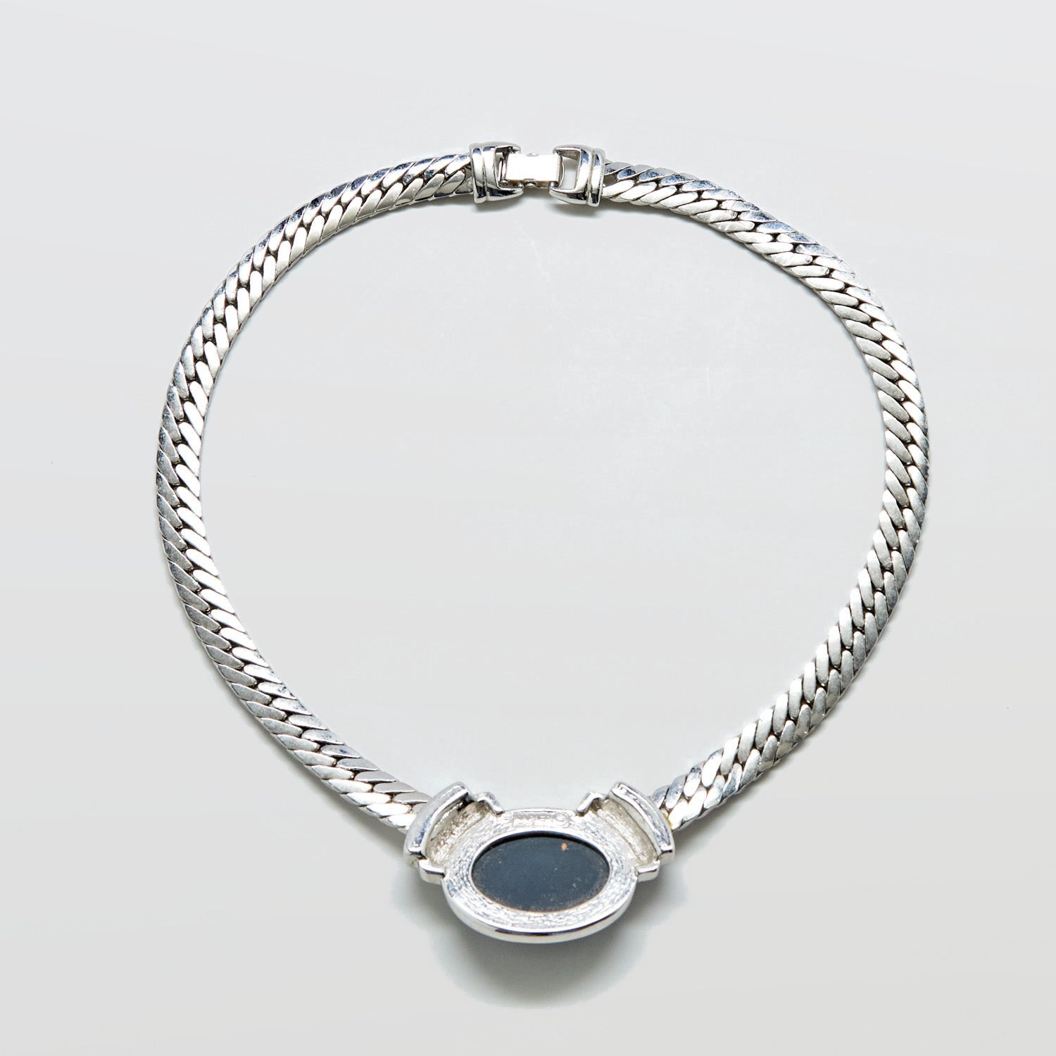 Silver chain necklace with a black stone on a light gray background