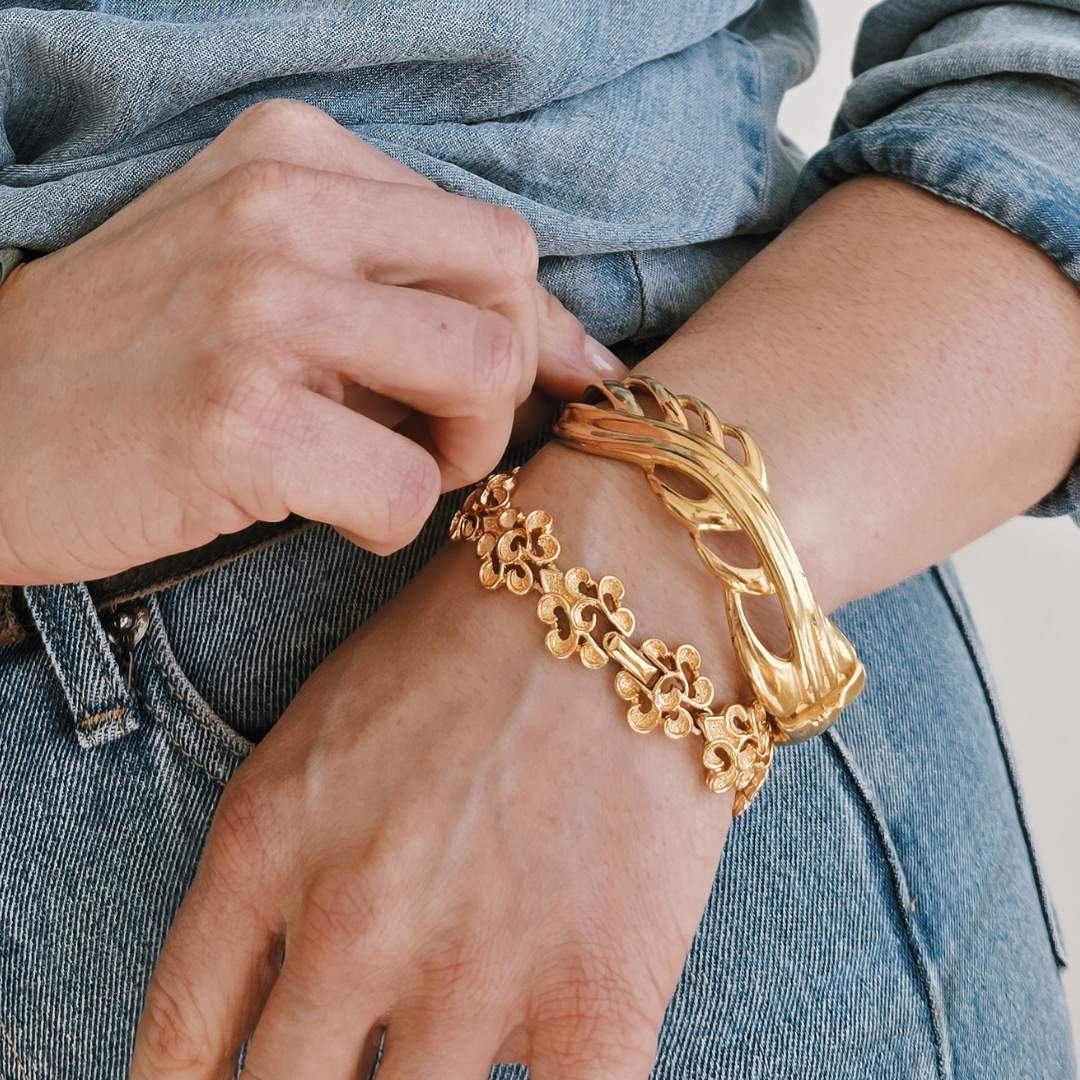 Person wearing a gold bracelet on a denim background