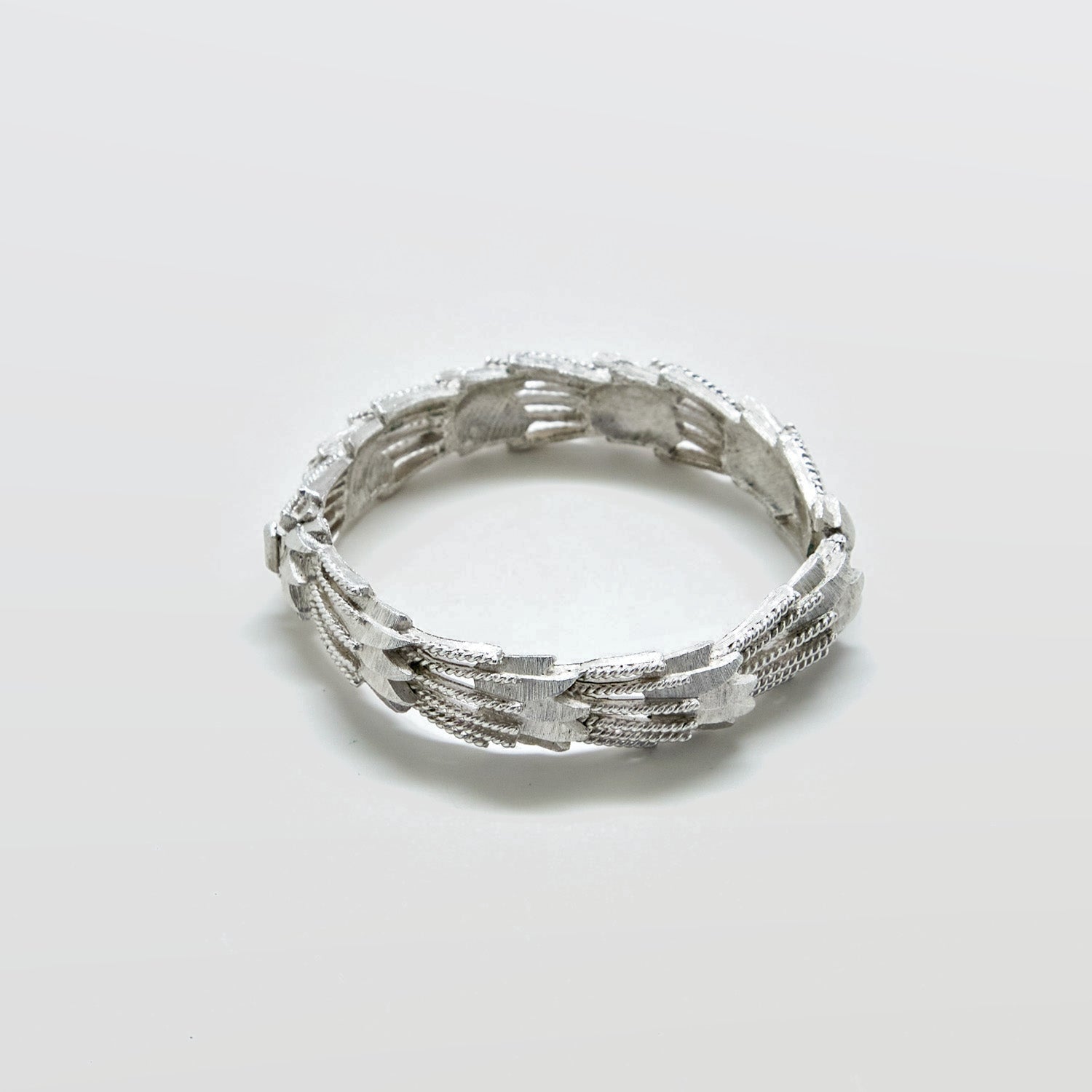 Silver ring with textured design on a light gray background