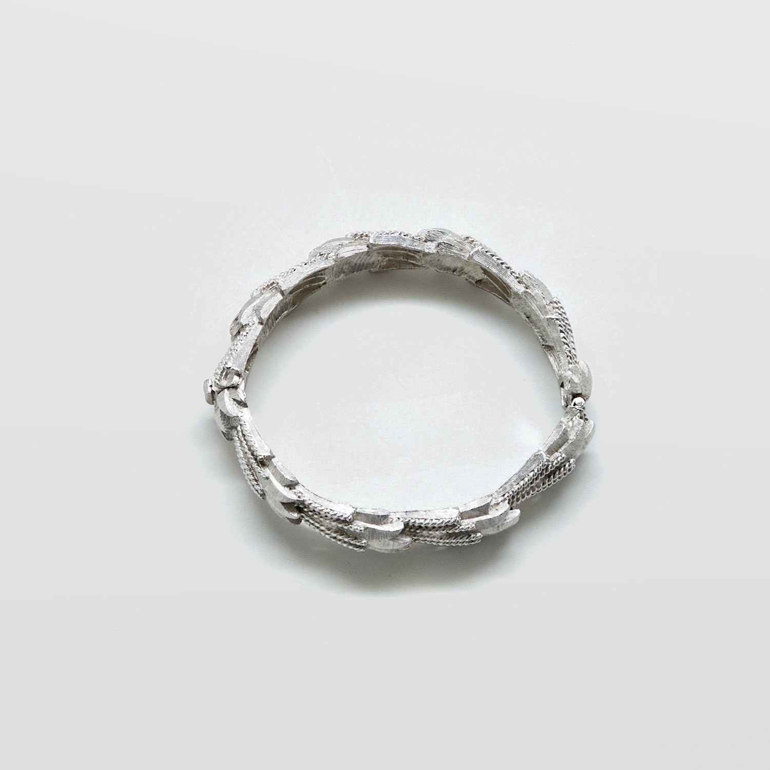 Silver ring with textured design on a light gray background