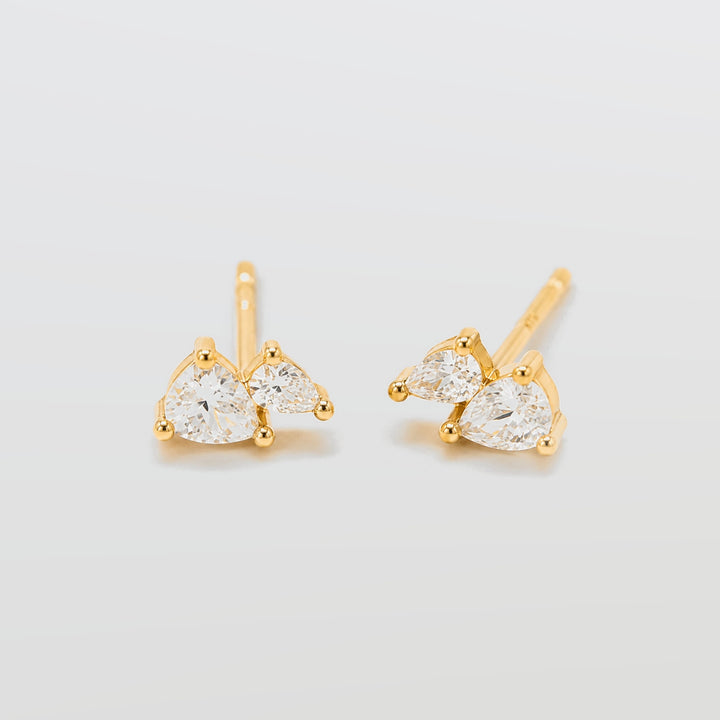 Gold earrings with clear gemstones on a light gray background