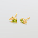 Gold earrings with green gemstones on a light gray background
