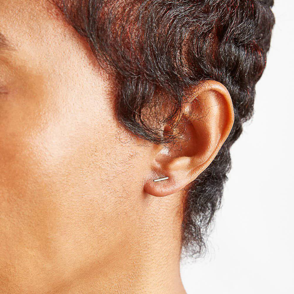 Close-up of an ear with a small earring on a neutral background